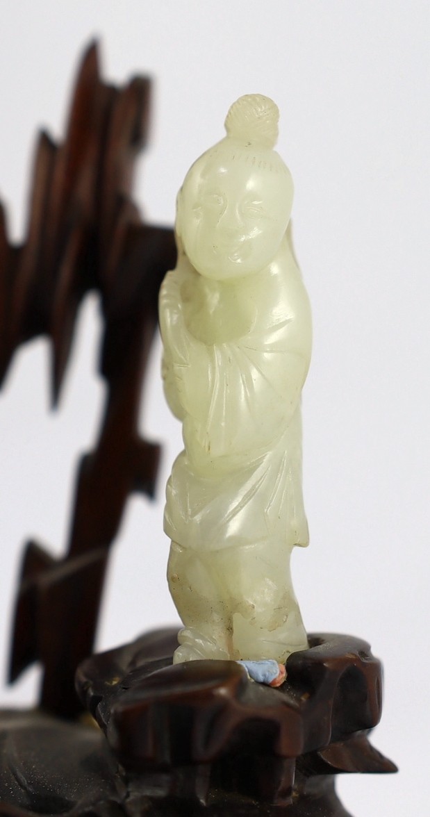 An assembled group of four Chinese pale celadon jade figures, 18th/19th century, displayed on two later wood 'rock-work' stands, total height approximately 19cm high